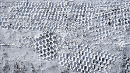 Car tire tracks on fresh snow in winter. Traces of tires on snow close up. Car or truck tyre mark on the snow.