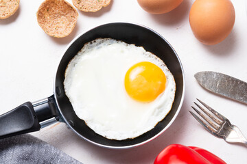 Scrambled, frying  eggs from one egg in a small pan on porcelain plate