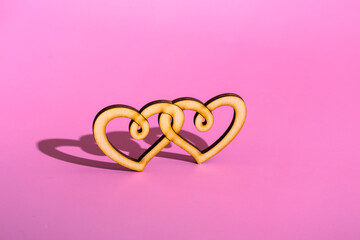 Wooden double heart on a pink background. Celebrating Valentine's Day copy space.