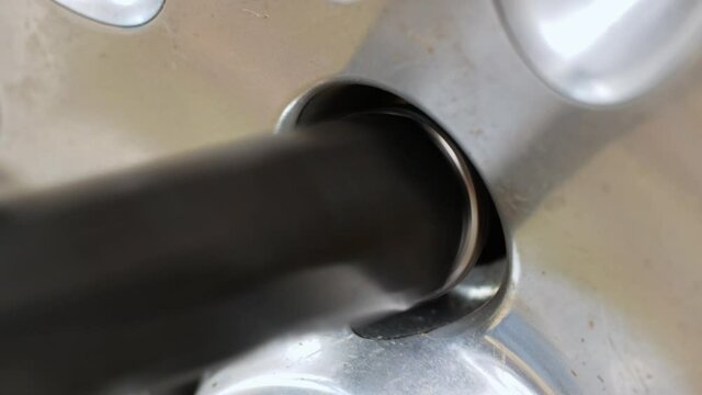 Close-up of a complete unscrewing of a car wheel nut at a car service center with a special tool