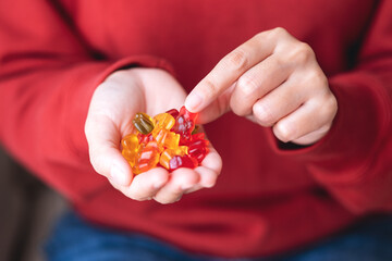 Closeup image of a woman holding and picking a jelly gummy bear