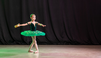 A little girl ballerina is dancing on stage in a tutu on pointe shoes with a tambourine, a classic variation of Esmeralda.