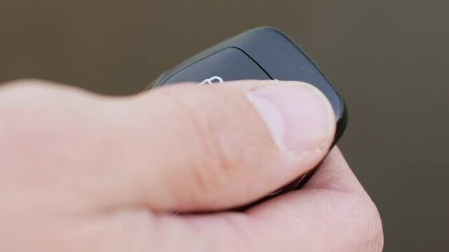 Man locks and unlocks car with key fob close-up on light gray background