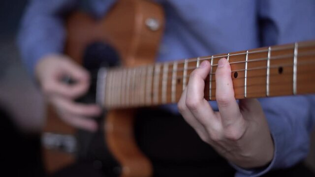 Guitar player in guitar workshop, repair of musical instruments, dealing guitars for people. Concept of art and music education