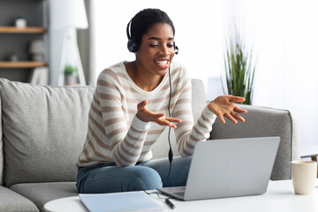 Naklejka premium Virtual Meeting. Cheerful Black Lady With Laptop And Headset Making Video Call