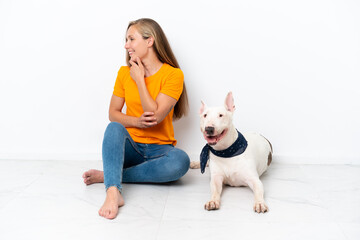 Obraz premium Young English woman sitting on the floor with her dog isolated on white background looking side