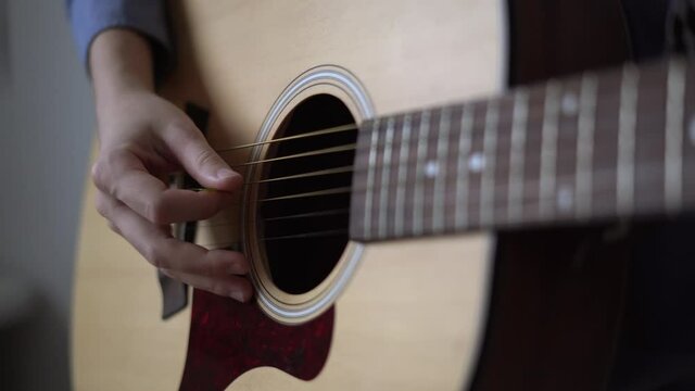 Guitar player hand with pick on strings of acoustic guitar. Pop acoustic ballad, sample pack for singer songwriter. Concept of music school and production