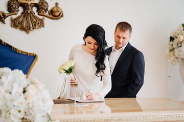 bride and groom in registry office sign official registration of marriage.