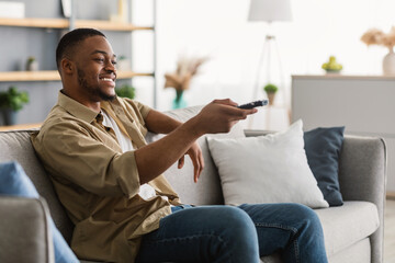 Obraz premium Happy African American Man Watching TV Switching Channels At Home