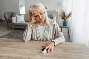 Senior woman using Oximeter at home. Healthcare Concept