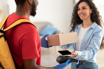 Black man holding POS terminal client paying with smart phone