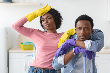 Exhausted african american man and woman resting while cleaning