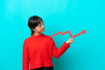 Young woman isolated on blue background holding a catching a rising arrow with happy expression