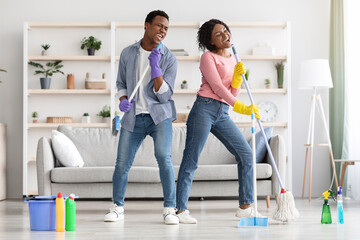 Funny african american family having fun while cleaning apartment