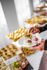 man hands take a snack and put it on plate. buffet in a restaurant