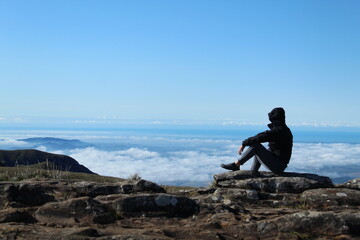homem no topo da montanha com mar de nuvens ao fundo 