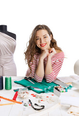 Smiling cute young girl, seamstress, dressmaker working with fabric, scissors and sewing machine isolated on white background. Concept of job, hobby