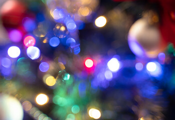 A defocused image of a decorated Christmas tree with garlands at Night.