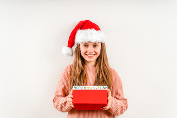 A smiling little girl in a red Christmas hat holds a New Year's gift. Holiday banner.