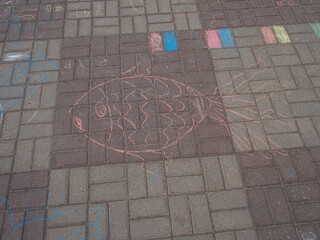 Children's drawings on the asphalt. The image of the sun applied with chalk on the surface of the paving slabs
