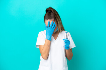Dentist caucasian woman holding tools isolated on blue background with tired and sick expression