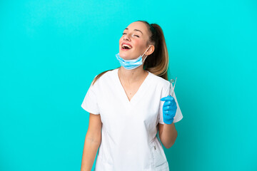 Dentist caucasian woman holding tools isolated on blue background laughing