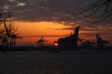Fototapeta na wymiar Dunkler Oranger Sonnenaufgang über den Hamburger Hafen im Herbst
