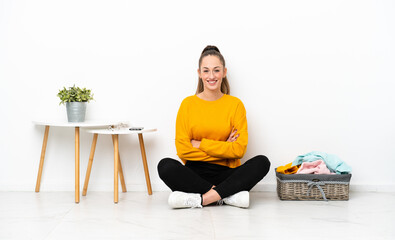 Young caucasian woman folding clothes sitting on the floor isolated on white background keeping the...
