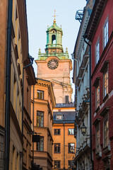 Low-angle view of historical buildings on the Stora Gramunkegrand Alley and the tower of the Saint Nicholas Church in winter day at sunset, Stockholm, Sweden
