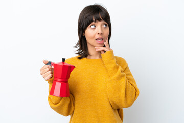 Young mixed race woman holding coffee pot isolated on white background thinking an idea while looking up