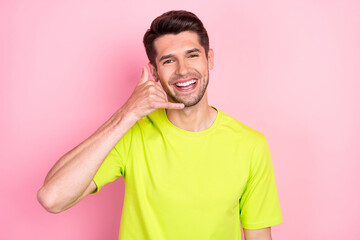 Portrait of attractive cheerful guy showing call me sign pretending talk on phone isolated over...