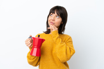 Young mixed race woman holding coffee pot isolated on white background and looking up