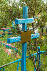 A grave cross with nameplate closeup in the Zaykovskoye Cemetery in sunny summer day, Kurgan, Russia
