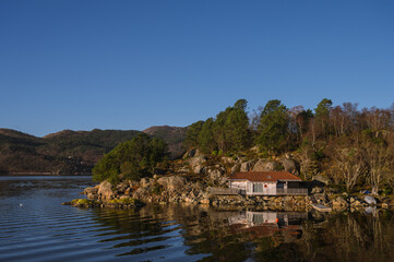 Fototapeta na wymiar Landscape of trees and house on rocky islands in Lusefjord. Fjord cruise. Tourism in Norway. Beautiful nature at sunny day.