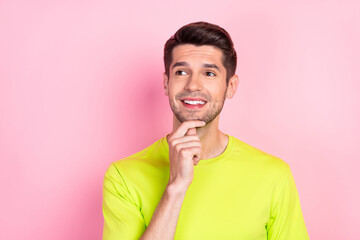 Photo portrait curious brunet man wearing bright t-shirt looking blank space got idea isolated pastel pink color background