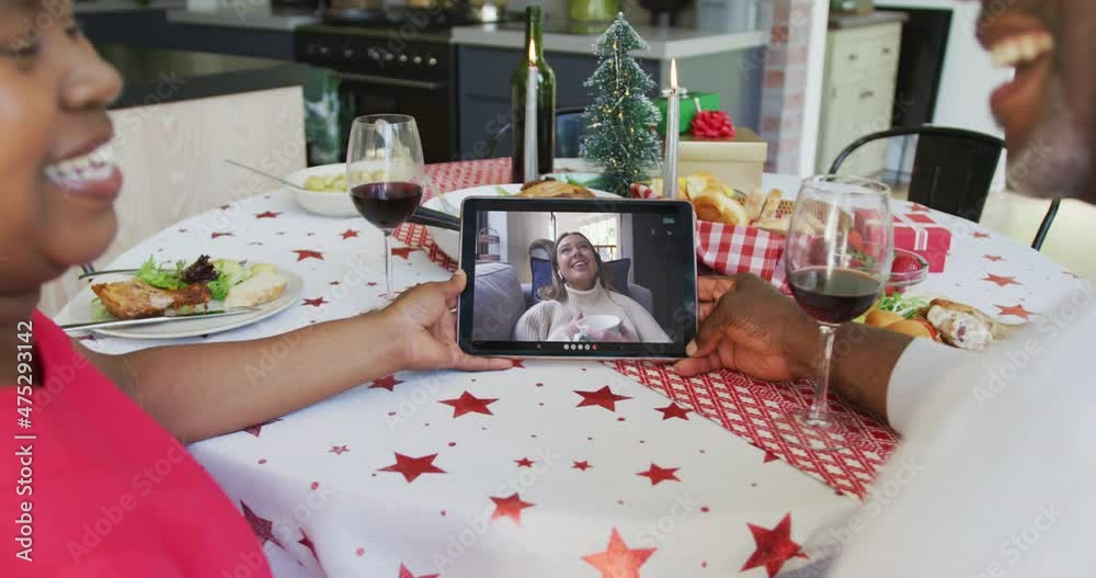 Sticker Smiling african american couple using tablet for christmas video call with happy woman on screen