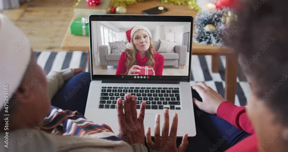 Poster African american mother and daughter using laptop for christmas video call with woman on screen