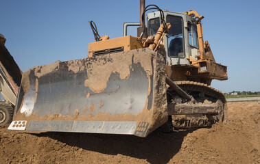 powerful heavy crawler bulldozer works at a construction site on a hot sunny day. Construction equipment for earthworks. Dozer blade close up © Anna