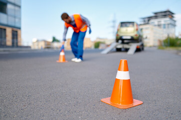 Road assistance worker putting cones near evacuator