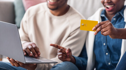 Black couple using computer and credit card at home