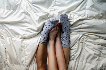couple's feet together with fluffy socks on bed