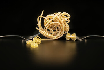 Creative still life photo of two forks with raw pasta on black background
