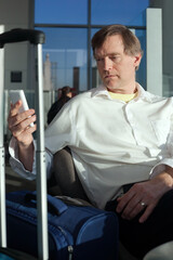 Businessman relaxing in airport terminal while using his cellphone