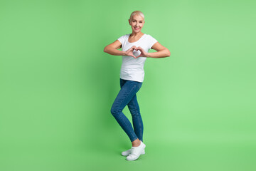 Obraz premium Full body profile side photo of lovely aged woman show fingers heart symbol cupid cardiac isolated over green color background