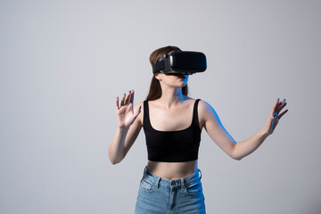 Close up of young woman stands in studio wearing VR glasses and swiping scrolling zooming with hands in a virtual space while interacting with a objects in a social networks.