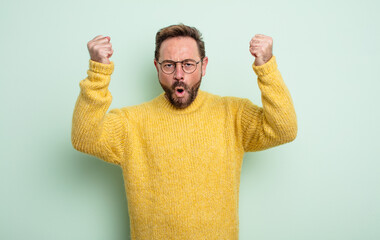 middle age handsome man celebrating an unbelievable success like a winner, looking excited and...