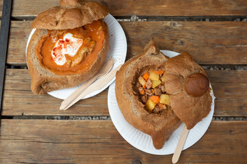 Hungarian goulash in bread bowl on wooden table. Street food in Budapest,  Hungary.