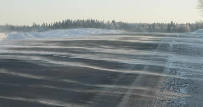 wind blowing snow on a country road. winter frosty day