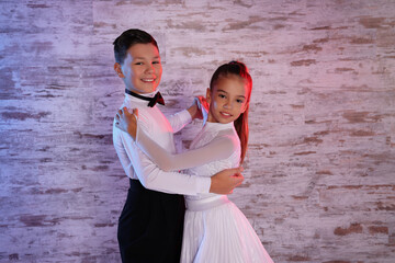 Beautifully dressed couple of kids dancing together in studio