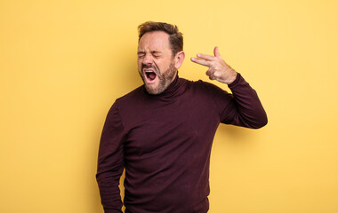 middle age handsome man looking unhappy and stressed, suicide gesture making gun sign with hand,...